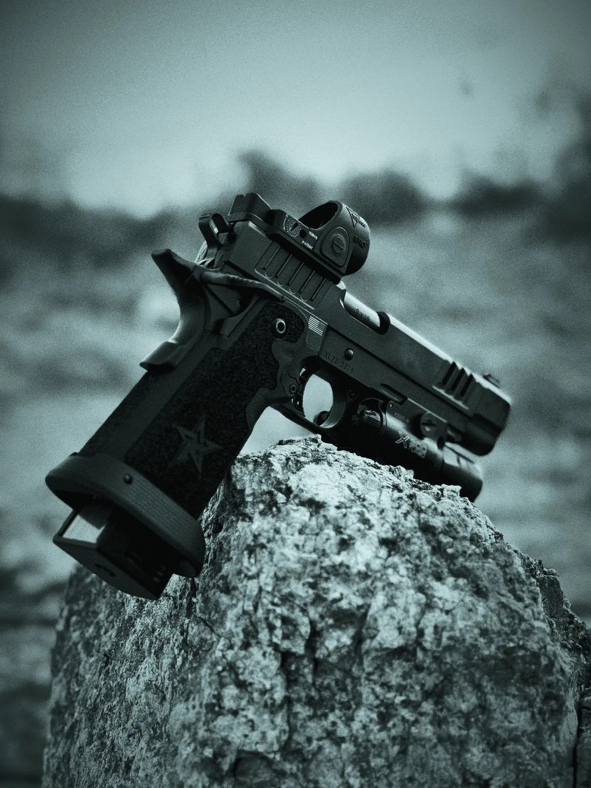 Handgun with a mounted red dot sight resting on a desert rock